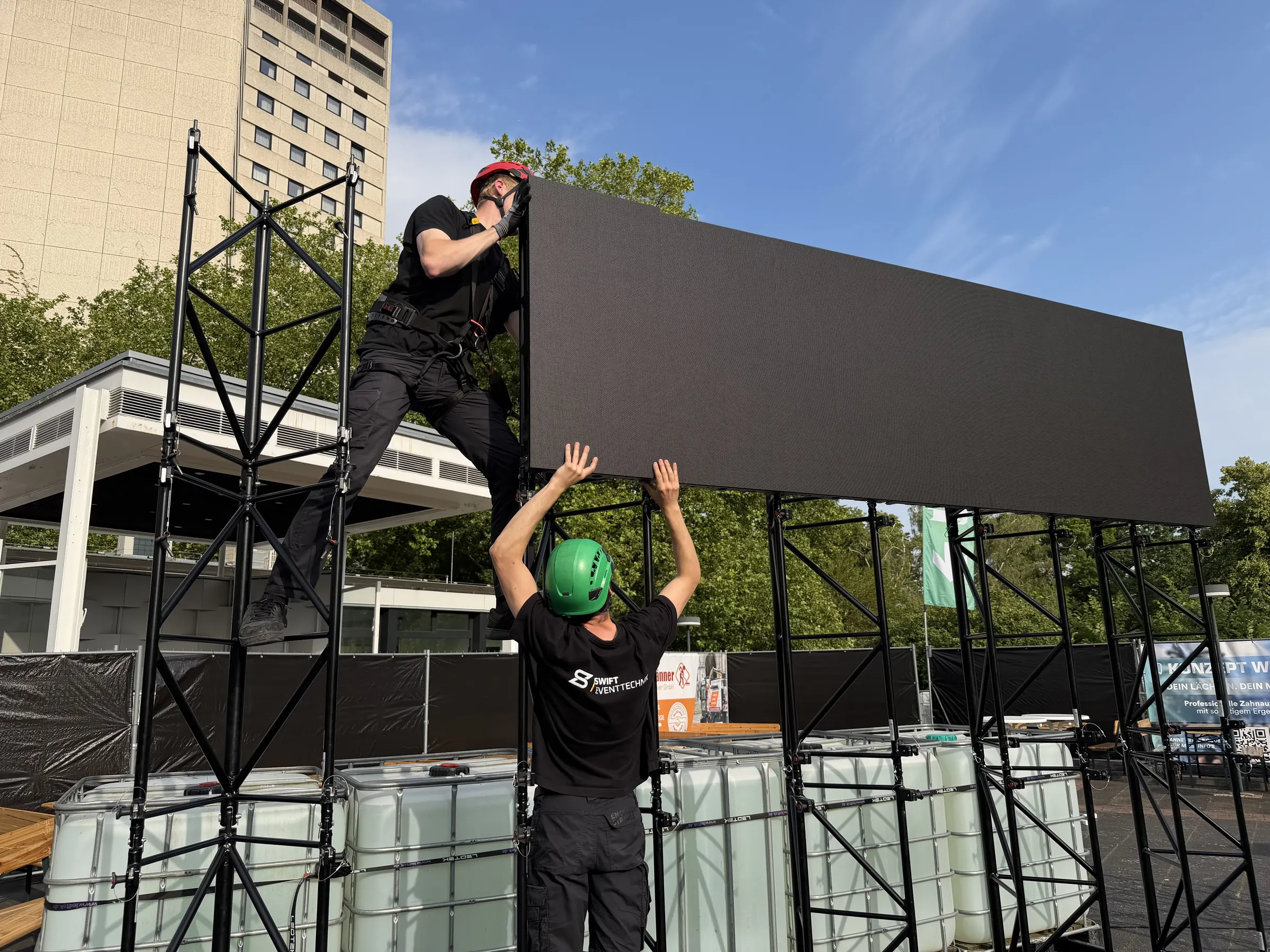 Zwei Techniker von SWIFT Eventtechnik montieren eine LED-Wand im Freien