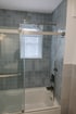 Bathroom with blue tiled walls, white bathtub, clear glass shower door, and a shower head.