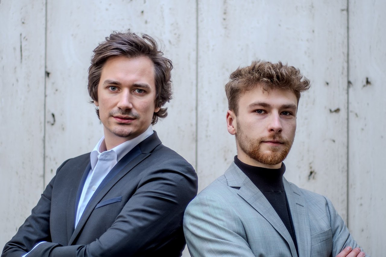 Die beiden Gründer von UPGRADS vor einer Betonwand