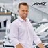 Lächelnder Mann im weißen Hemd im Autohaus mit AMZ Automobilzentrum Memmingen GmbH Logo