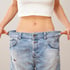 Woman holding loose jeans after clinical nutrition & weight loss treatment