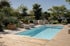 Ein rechteckiger Swimmingpool mit Holzterrasse, modernen Loungemöbeln und mediterranen Pflanzen in einem Garten.