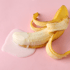 Geschälte Banane mit weißer und rosa Flüssigkeit auf rosa Hintergrund.