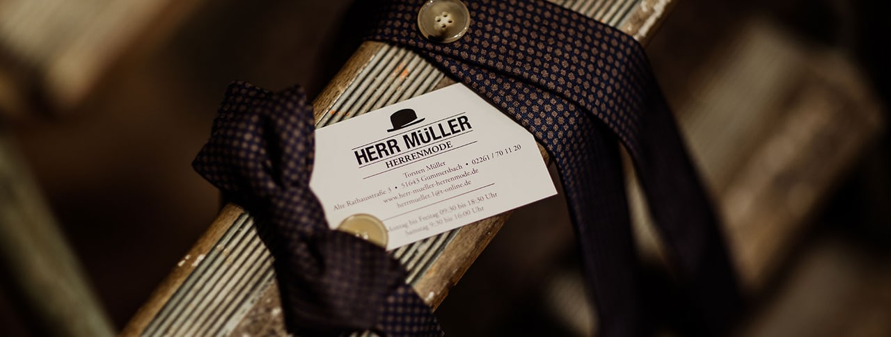 Visitenkarte von Herr Müller Herrenmode, um eine Krawatte gebunden