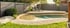 Moderner Swimmingpool mit Rasenfläche, Sonnenliege und einem Gartenhaus mit Außenbar und großen Glasfronten.