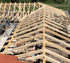 Neuer Dachstuhl aus hellem Holz auf einem Gewerbegebäude und Gerüsten.