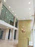 Moderne Lobby mit hohen Decken, eingelassenen Lichtern, Glasfassade und hängenden Kupferlampen.