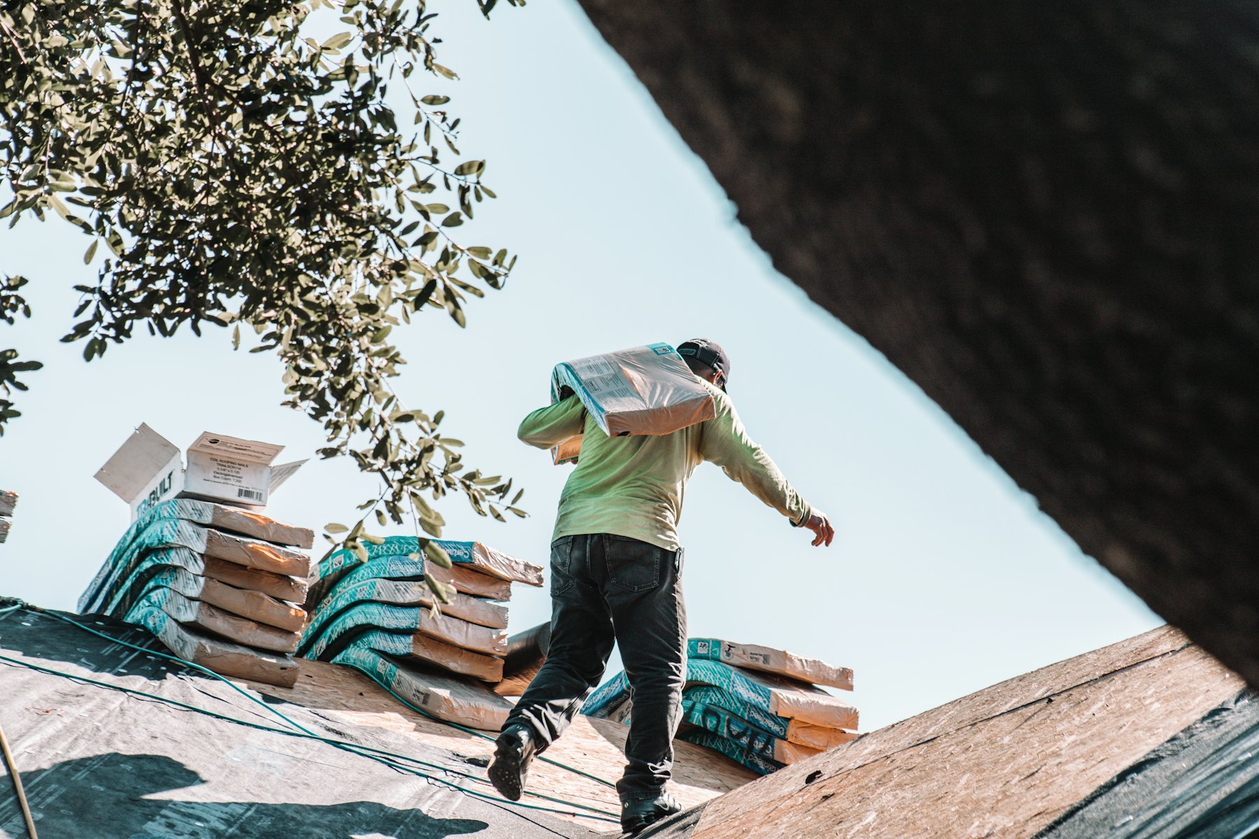Roofer carrying a shingle bundle across a roof deck, roof replacement cost in Fort Worth