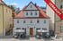 Historisches Gebäude mit Restaurant Baggersla, Außengastronomie und rotem Banner mit der Aufschrift verkauft.