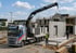 LKW mit Ladekran hebt eine Betonfertigteilwand auf einer Baustelle für ein Mehrfamilienhaus an.