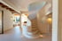 Elegante weiße Wendeltreppe in einem hellen, modernen Interieur mit Holzbalken und Bögen.