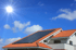Solarmodule auf einem Ziegeldach unter blauem Himmel mit strahlender Sonne.
