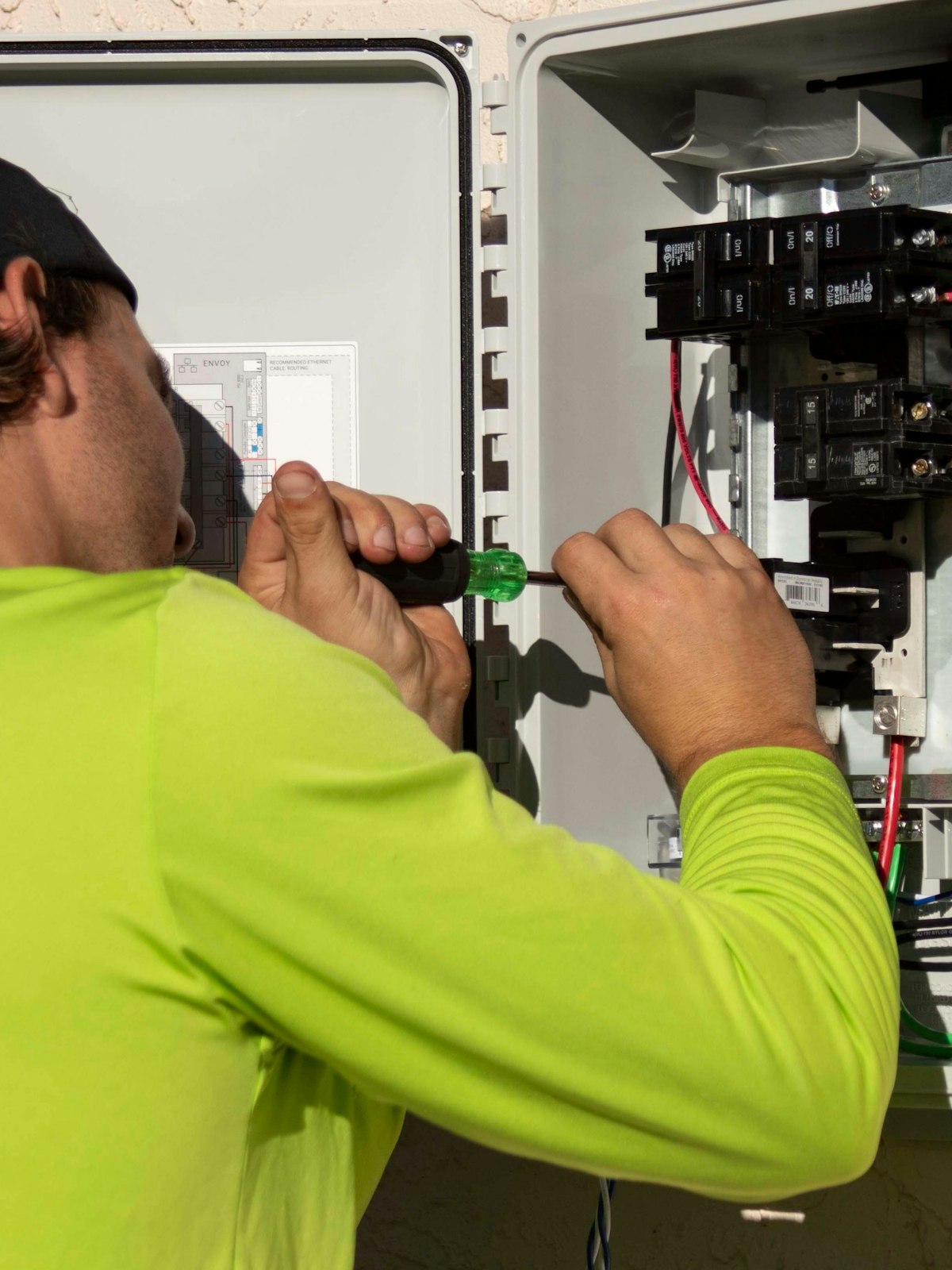Electrician working inside an open residential electrical panel
