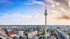 Berliner Fernsehturm über der Stadtlandschaft mit Gebäuden unter blauem Himmel mit Wolken.