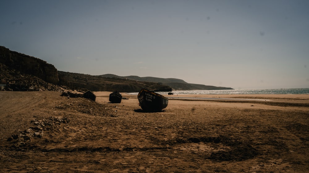 Strand mit alten Booten und Hügeln im Hintergrund