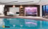 Innenansicht eines modernen Wellnessbereichs mit Pool, Ruheliege und einer Sauna mit farbiger Beleuchtung.