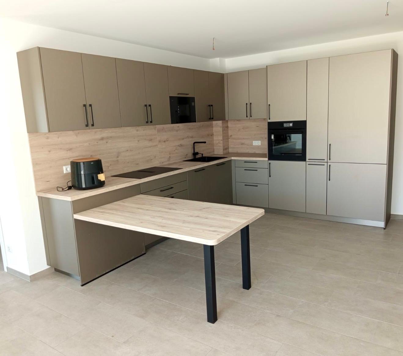 Küche in Champagner metallic mit Rückwand in heller Eiche und angesetztem Esstisch