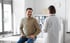 A male patient talking to a doctor in an examination room.