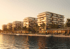 Modern waterfront apartment buildings with balconies and palm trees, bathed in golden hour sunlight.