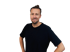 Mann mit dunklem T-Shirt und Bart, lächelnd in die Kamera blickend, Hände in den Hüften.