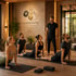 Ein Trainer beobachtet vier Personen bei Yoga-Übungen in einem Studio mit "ELEMENTS Longevity & Biohacking" Logo.
