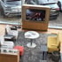 Lounge-Bereich in einem Autohaus mit Fernseher, der einen Mann beim Billardspielen zeigt, und mehreren Sitzgelegenheiten.