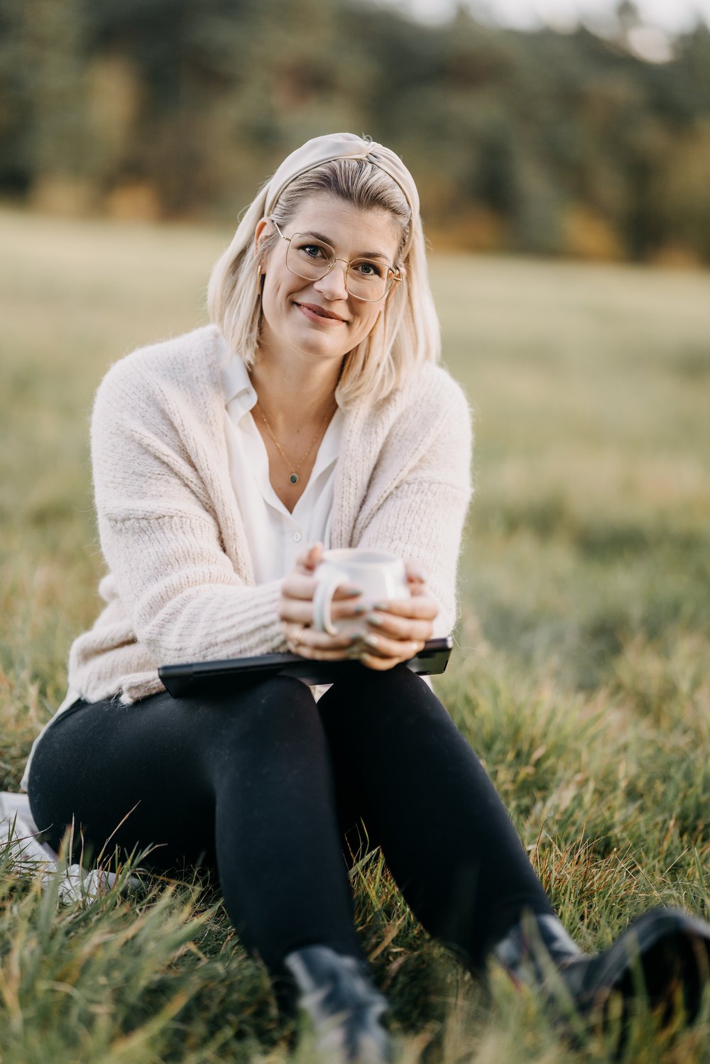 Sina sitzt mit Laptop und Tasse im Gras