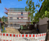 Baustelle mit Gerüst an einem dreistöckigen Haus und Solarpanelen, davor ein Bauzaun.