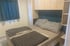 Ein kleines Schlafzimmer mit einem Bett, grau-karierter Bettwäsche und dunkelblauen Vorhängen.