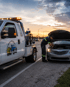 Towing Port Charlotte roadside assistance technician helping a stranded driver with a disabled car at sunset.