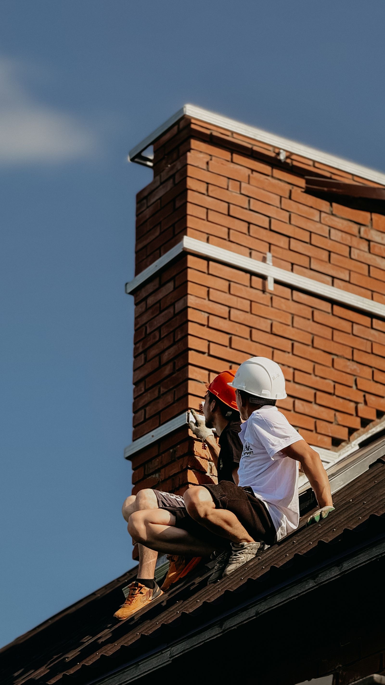 Roofers carrying out flashing work around a chimney