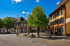 Ein sonniger Platz mit Bäumen, historischen Gebäuden und einem Brunnen in Schopfheim.