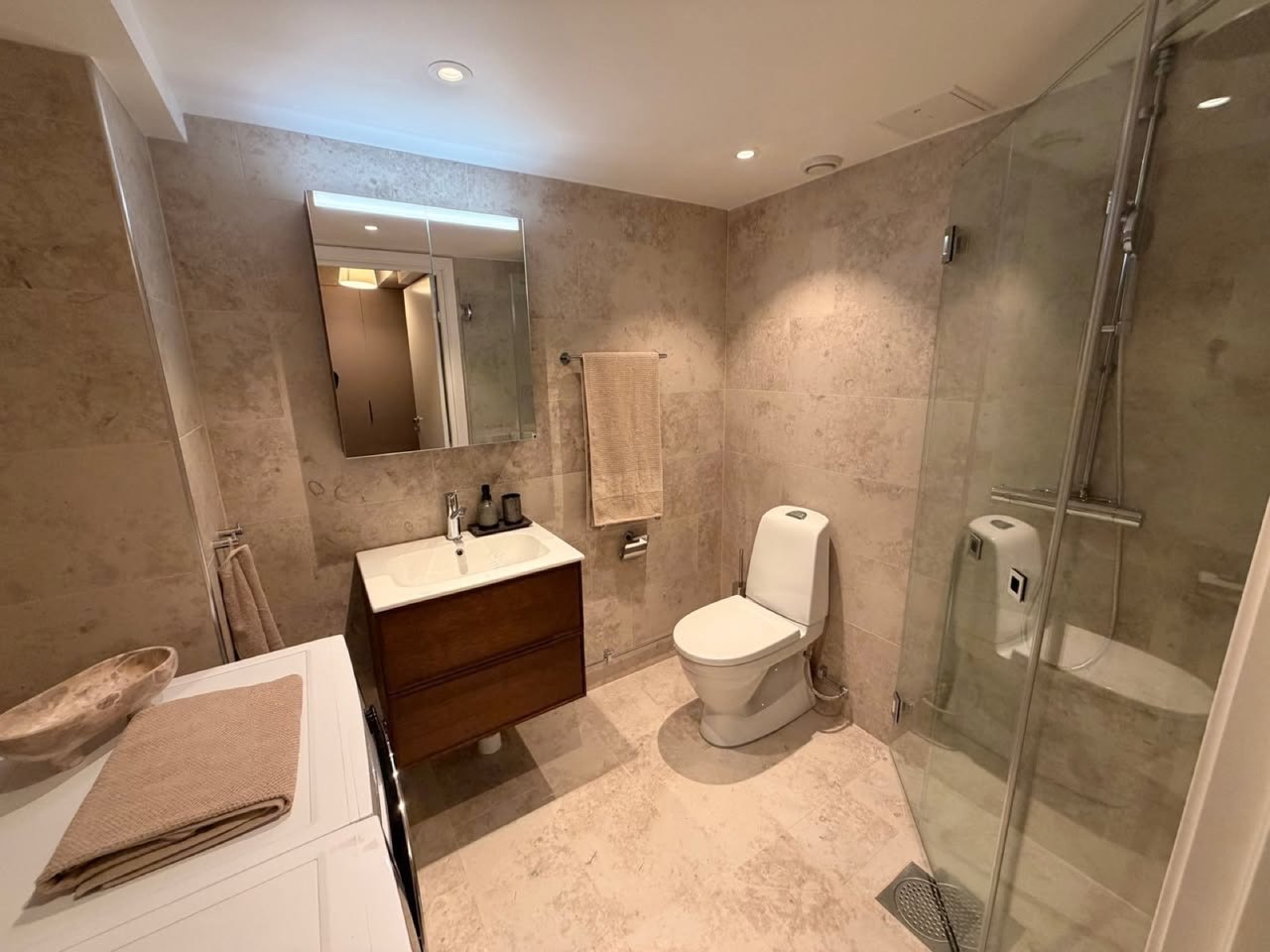 Badrum med stenklinker och duschhörna efter renovering