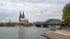 Kölner Dom und Hohenzollernbrücke über dem Rhein bei bewölktem Himmel.