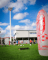 Fußballtraining auf einem grünen Feld mit Spielern, Flutlichtmast und einem roten aufblasbaren Keeperdummy.