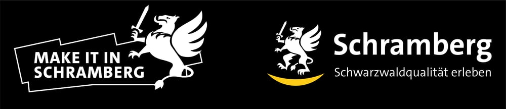 Weißes "MAKE IT IN SCHRAMBERG"-Logo mit einem geflügelten Schwein, das ein Schwert auf grünem Hintergrund hält.
