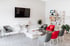 Modern office waiting room with grey and red armchairs, a wall-mounted TV, and retail display shelves.