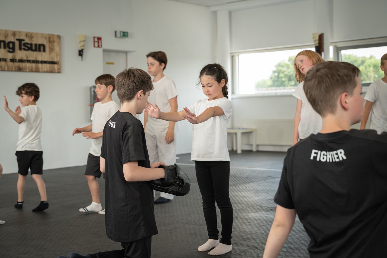 Kinder üben im Tiger-Kurs gemeinsam Abwehrbewegungen