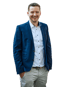 Dennis Willen im Anzug. Hintergrund Transparent. Wird angezeigt vor einem seiner Immobilien Objekte.