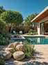 Moderner Garten mit Pool, Felsen, Pflanzen, Holzterrasse und Pergola.