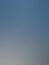 Industrielle Rohrleitungen aus Edelstahl mit Manometer und blauen Ventilen in einem blauen Technikraum.
