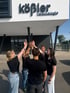 Fünf Personen in schwarzer Kleidung geben sich vor dem Gebäude von Kößler Technologie High Five.
