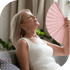 Senior woman holding a handheld fan, relaxing after menopause therapy