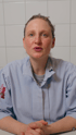 Eine Frau in einem blau-weiß gestreiften Hemd mit der Aufschrift „METZGER BUNK“ blickt in die Kamera.