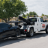 Towing Deltona wheel lift towing service safely lifting a black car for roadside transport in a residential neighborhood