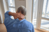 A person from behind rubs their neck, experiencing pain.