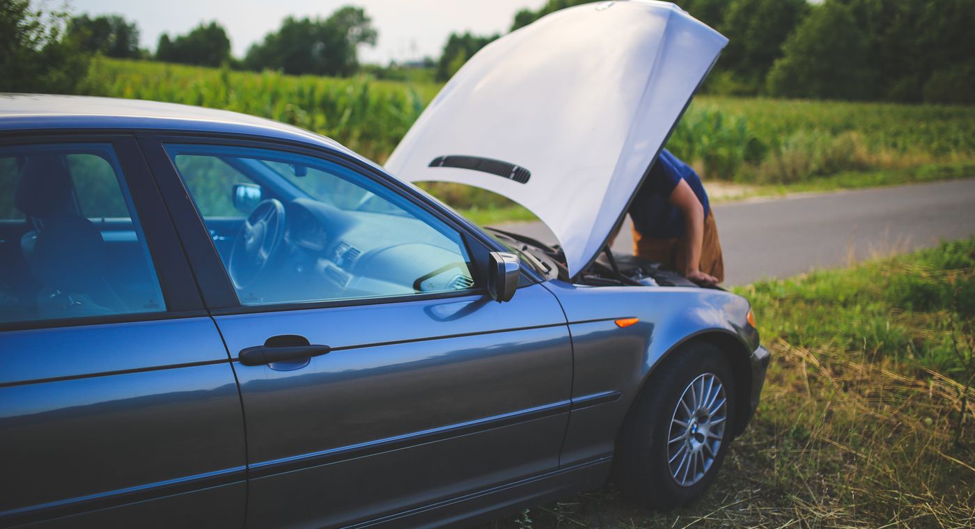 What to do if your car overheats: a driver checking an overheated engine on the roadside near Orlando, FL