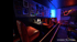 Dunkles Restaurant mit roten Ledersitzbänken, Tischen, beleuchteten Wänden und Gitarren-Neonlicht.