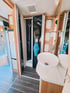 Badezimmer in einem Wohnmobil mit Dusche und ovalem Waschbecken.