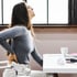 
A woman holding her lower back in pain at a desk.







